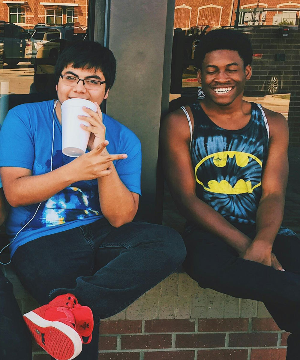 Two teen boys sitting outside school hanging out